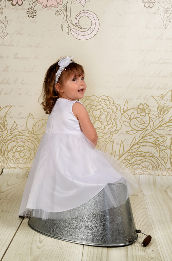 Klasyczna i prosta sukienka do chrztu Naomi wykonana z wysokiej jakości atłasu oraz miękkiego tiulu.